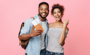 Pink background. A young couple holding a passport and two flight tickets. They look happy for the next adventure.